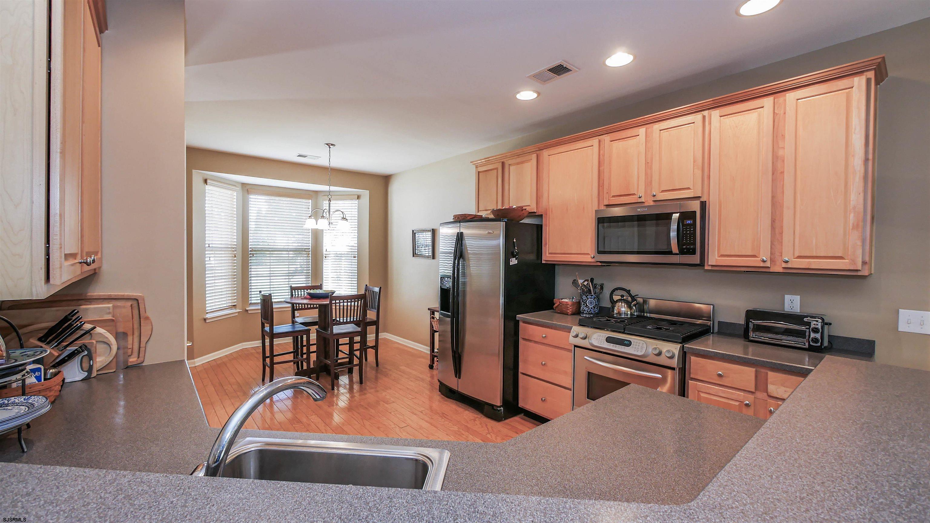 33 Brampton Street Smithville, NJ 08205 - Photo 11 of 37 a kitchen with stainless steel appliances granite countertop a stove top oven a sink a dining table and chairs with wooden floor