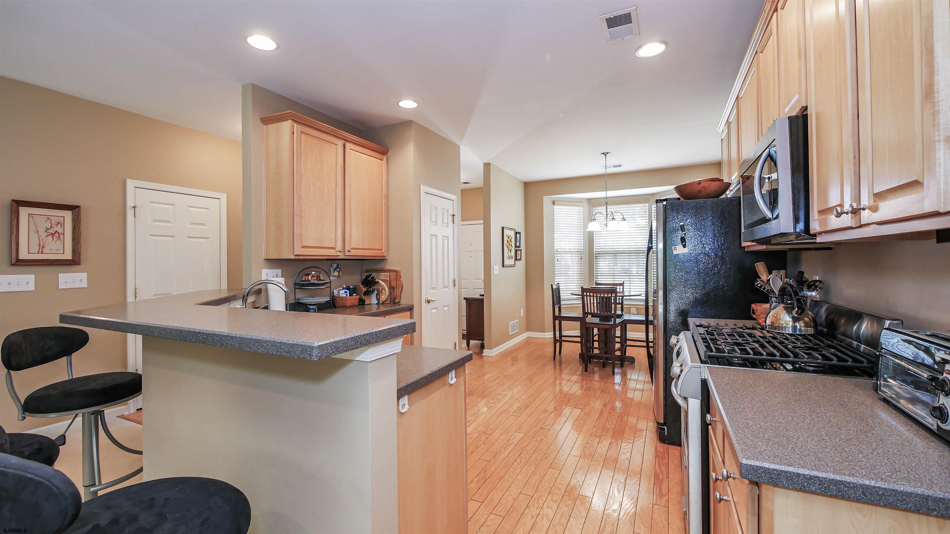 33 Brampton Street Smithville, NJ 08205 - Photo 10 of 37 a kitchen with stainless steel appliances granite countertop a refrigerator a sink dishwasher a stove and a dining table with wooden floor