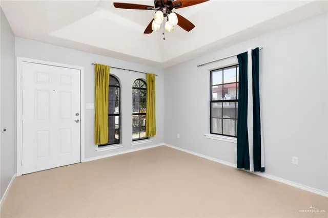 an empty room with windows and ceiling fan
