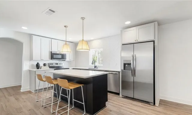 a kitchen with kitchen island granite countertop a sink a center island and stainless steel appliances