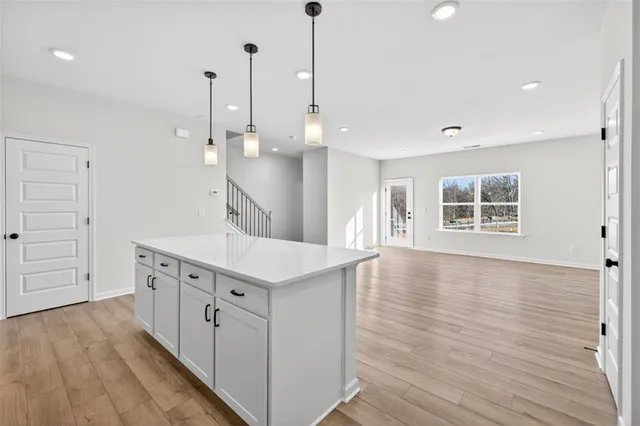 a kitchen with stainless steel appliances granite countertop a sink a stove a refrigerator and white cabinets with wooden floor