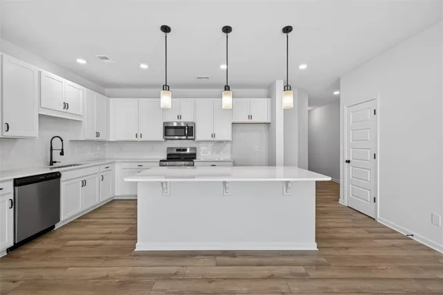 a kitchen with kitchen island a sink a stove a refrigerator and white cabinets