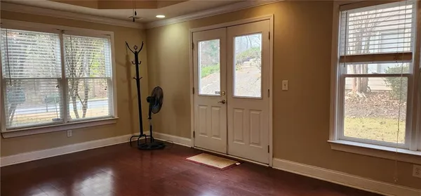 a view of an empty room with wooden floor and a window