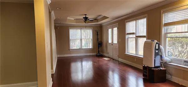 an empty room with wooden floor fan and windows