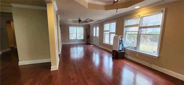 a view of empty room with wooden floor and fan