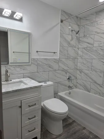 a bathroom with a granite countertop toilet sink and mirror