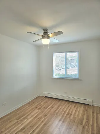 an empty room with a window and a ceiling fan