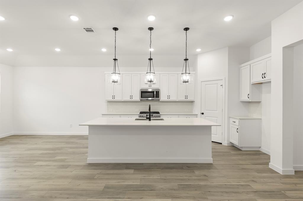 1821 Bachman Lane Forney, TX 75126 - Photo 12 of 27 a view of a kitchen with kitchen island a sink wooden floor and a large window