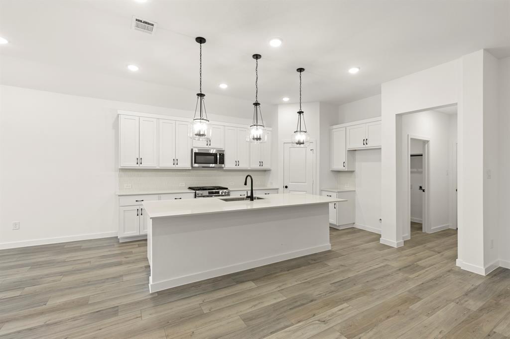 1821 Bachman Lane Forney, TX 75126 - Photo 13 of 27 a large kitchen with white cabinets and wooden floor