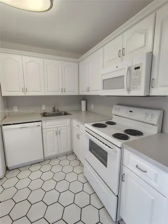 a white kitchen with granite top and stainless steel appliances