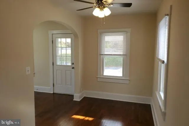 a view of an empty room with wooden floor and a window