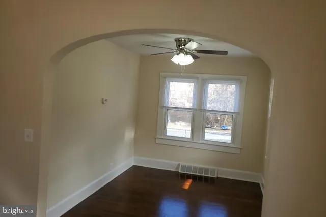 an empty room with windows and ceiling fan