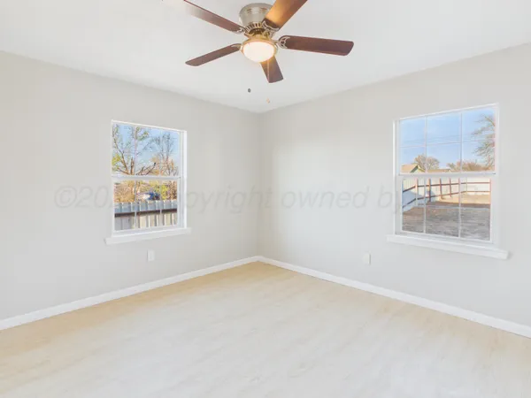 an empty room with windows and fan