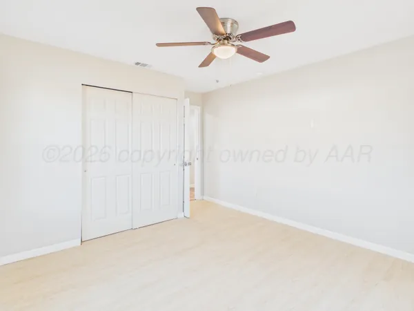 an empty room with a fan & a window