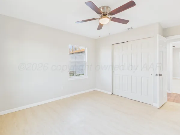 an empty room with windows and fan