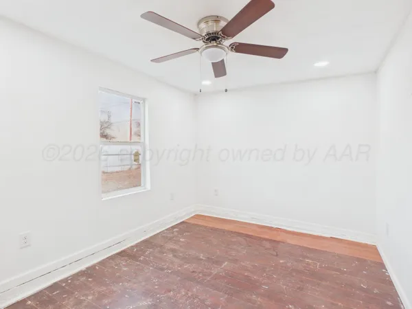 an empty room with a window and a fan