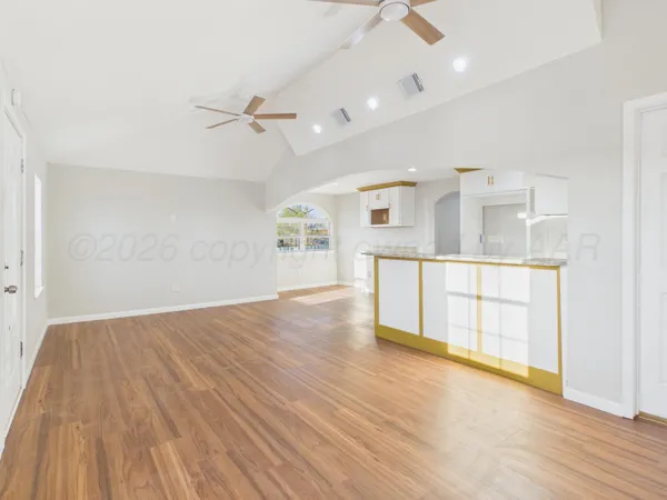 an empty room with wooden floor cabinet and windows