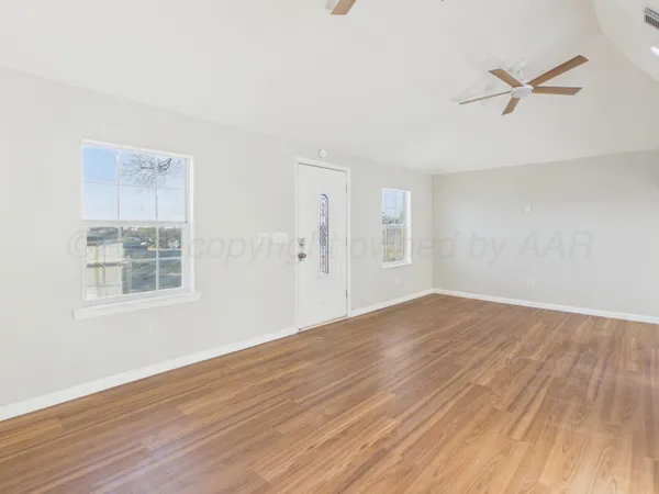 a view of empty room with wooden floor and fan