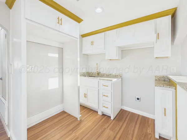 a room with white cabinets and wooden floor