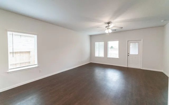 a view of an empty room with wooden floor and a window