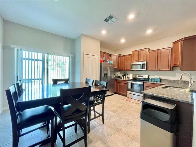 a kitchen with granite countertop wooden cabinets a dining table and chairs