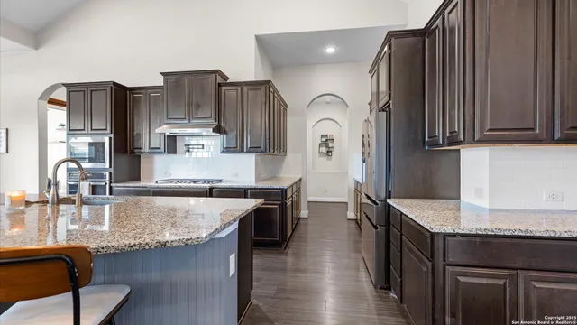 a kitchen with stainless steel appliances granite countertop a stove a sink and a refrigerator