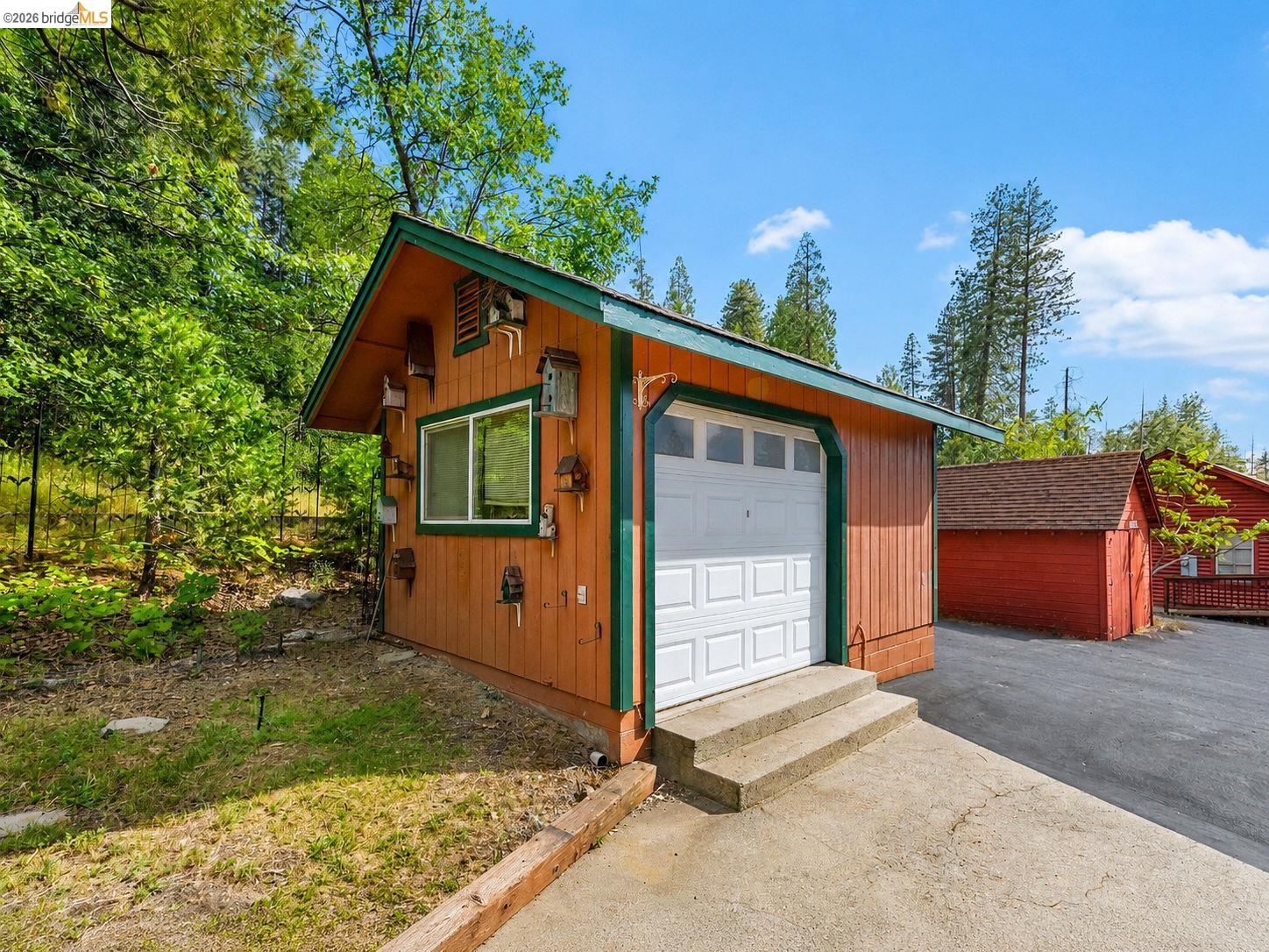22401 Ridge Road Twain Harte, CA 95383 - Photo 41 of 56 Detached structure featuring wood siding, a white garage door, and a single window with green trim