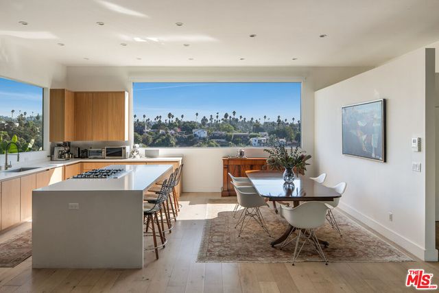 a view of a kitchen with kitchen island stainless steel appliances wooden floor dining table and chairs