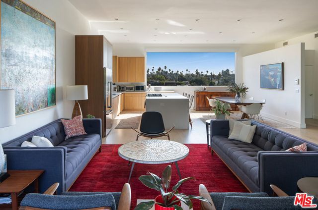 a living room with furniture a rug and kitchen view