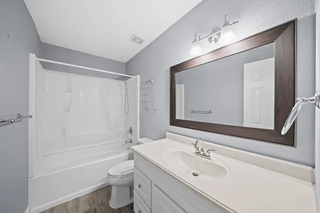 a bathroom with a toilet a sink a mirror a bathtub and vanity