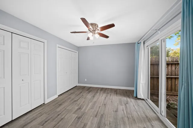 an empty room with wooden floor and a ceiling fan