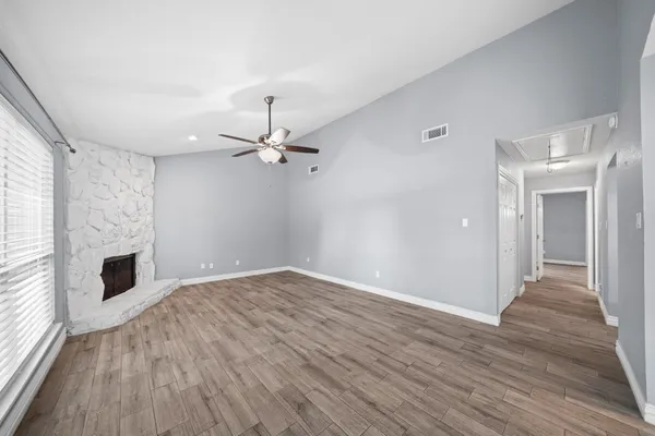 a view of empty room with wooden floor and fan