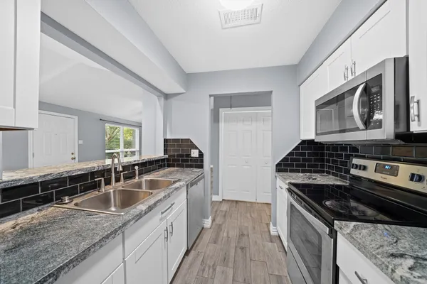 a kitchen with granite countertop stainless steel appliances a sink stove top oven and microwave