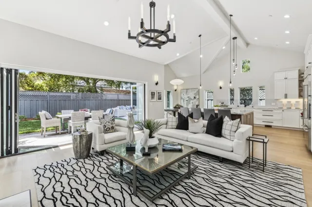 a living room with lots of furniture a chandelier and a large window