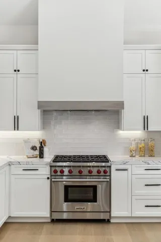 a kitchen with stainless steel appliances a refrigerator and white cabinets