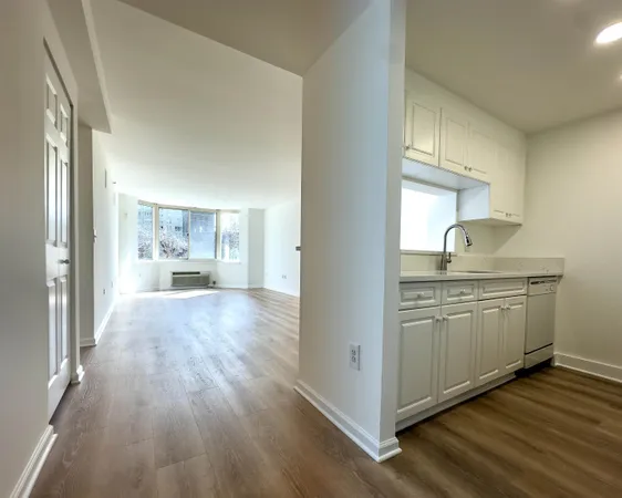 a open kitchen with granite countertop a refrigerator stove oven and white cabinets with wooden floor