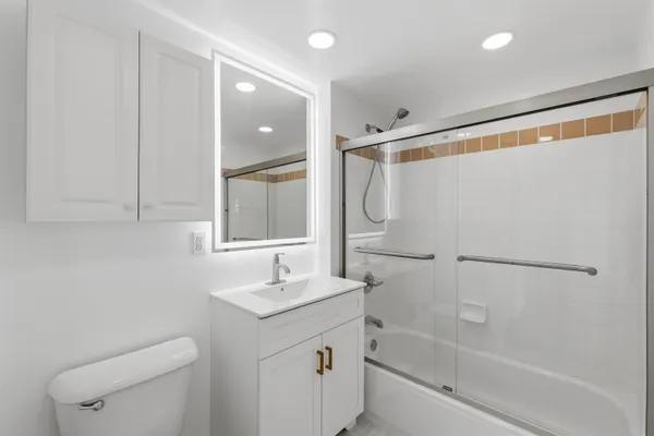 a bathroom with a shower sink vanity mirror and toilet