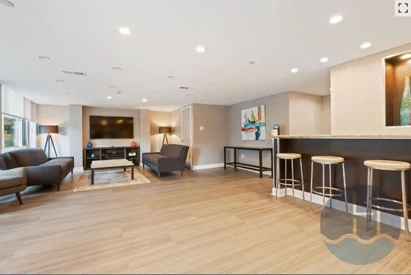 a living room with furniture a wooden floor and kitchen view