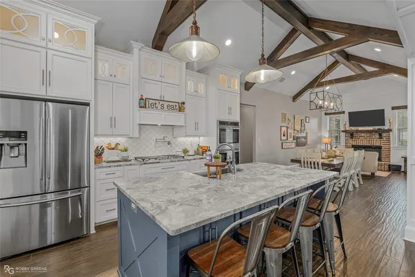 a kitchen with stainless steel appliances granite countertop a table chairs sink refrigerator and microwave