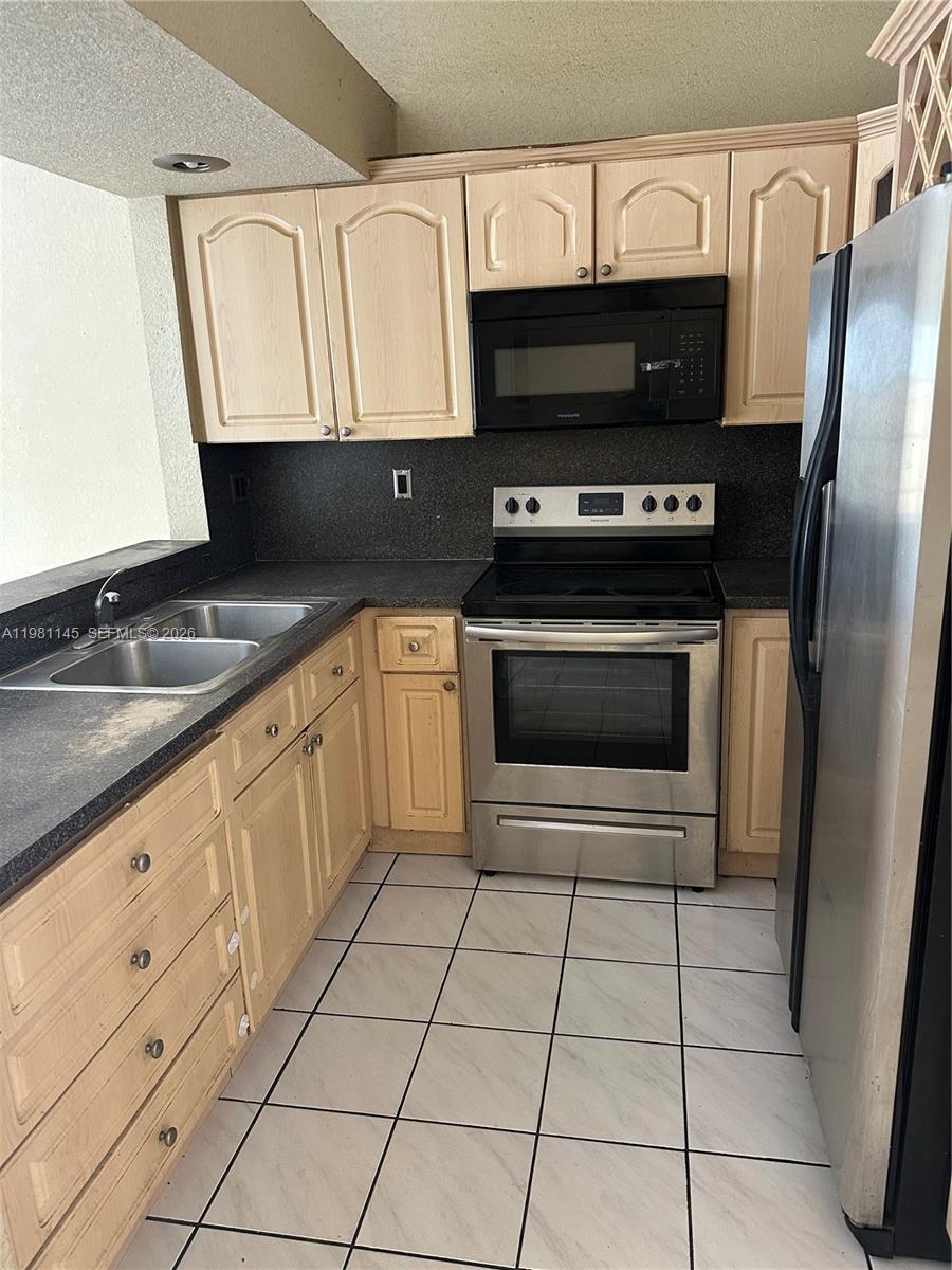 5861 Southwest 152nd Court Miami, FL 33193 - Photo 4 of 26 a kitchen with granite countertop a stove a sink and a microwave