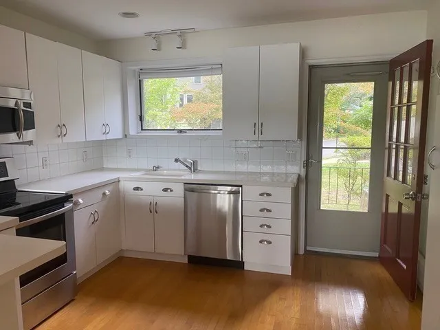 a kitchen with white cabinets and window