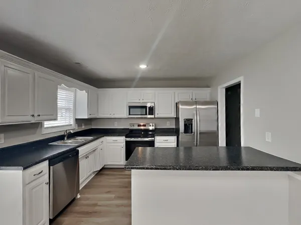 a large kitchen with stainless steel appliances granite countertop a lot of counter space