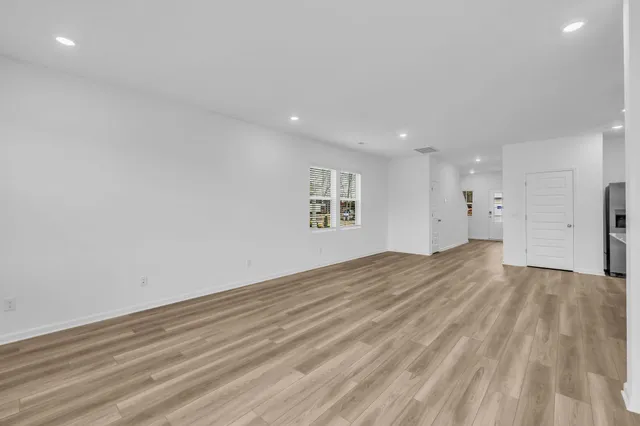 a view of empty room with wooden floor and windows