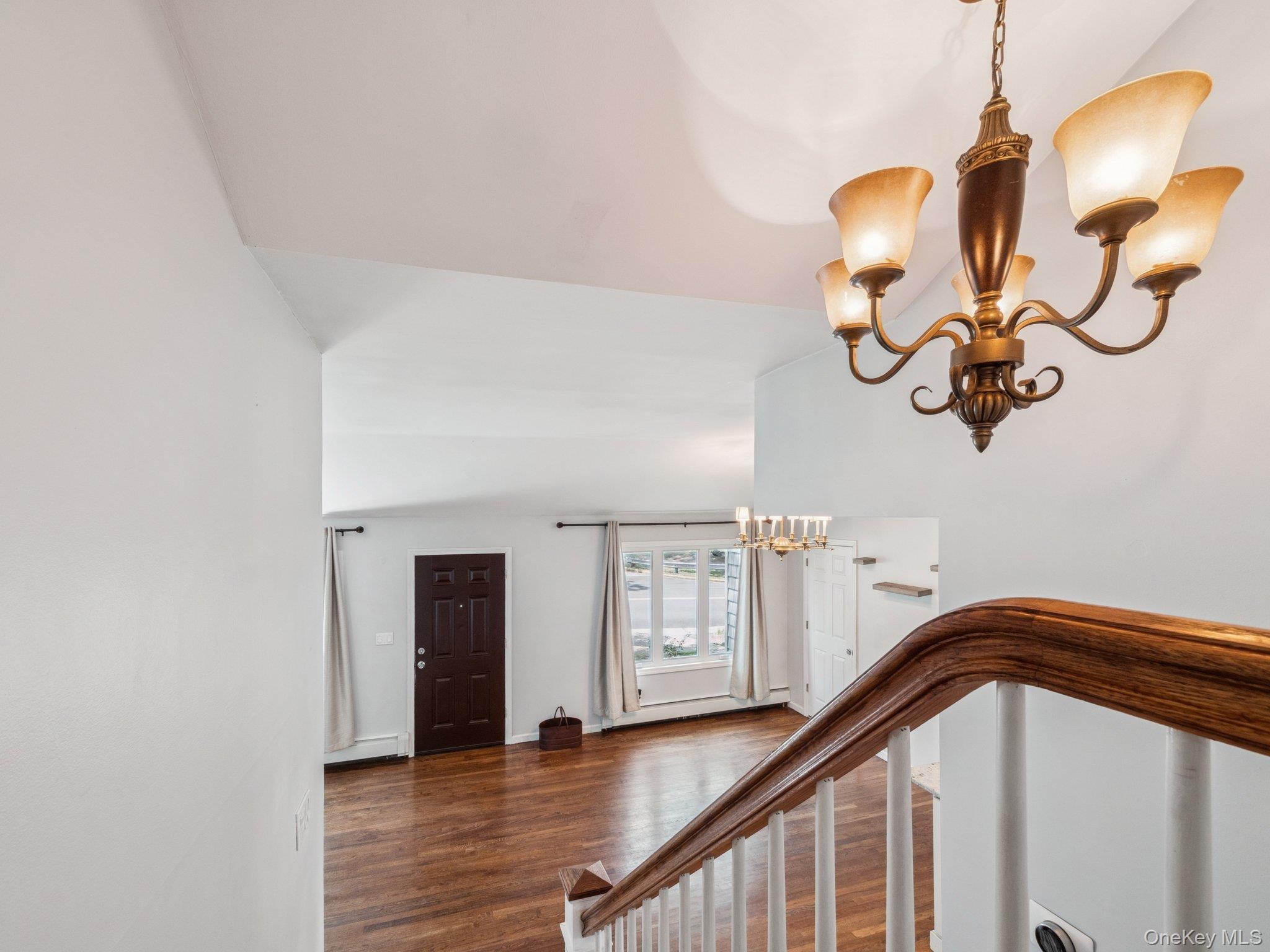 247 Woods Road North Babylon, NY 11703 - Photo 16 of 43 a view of a hallway with wooden floor and a chandelier