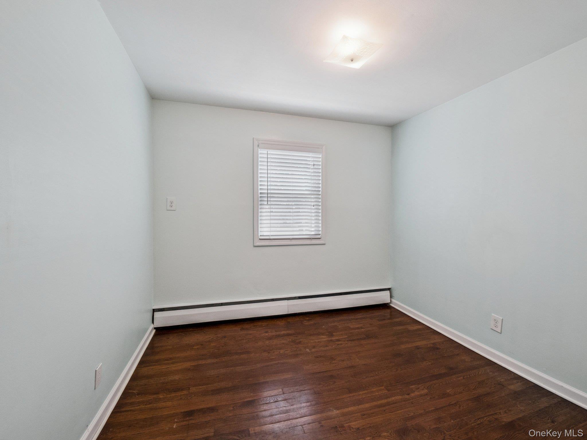 247 Woods Road North Babylon, NY 11703 - Photo 17 of 43 a view of an empty room with wooden floor and a window