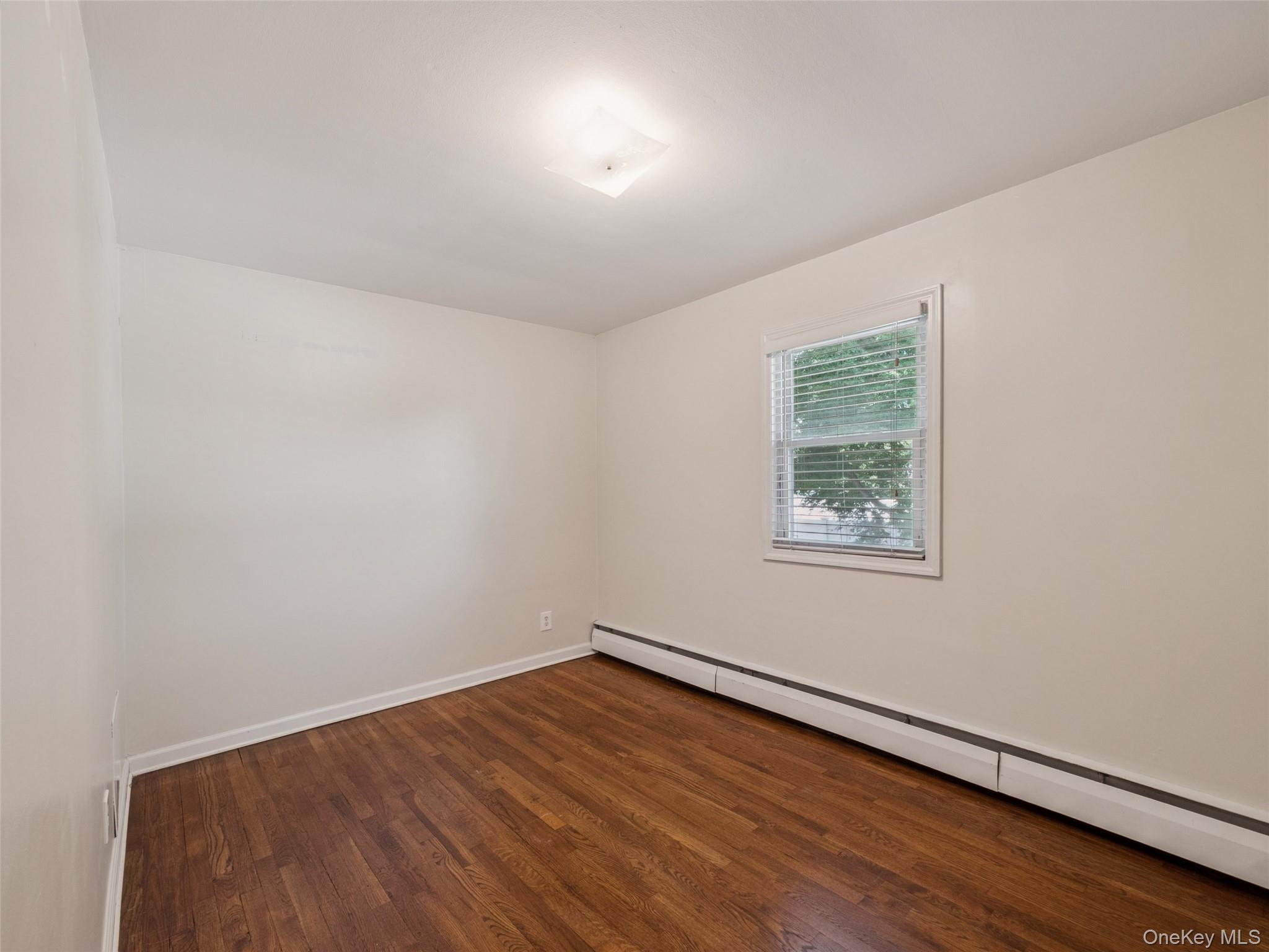 247 Woods Road North Babylon, NY 11703 - Photo 21 of 43 an empty room with wooden floor and windows