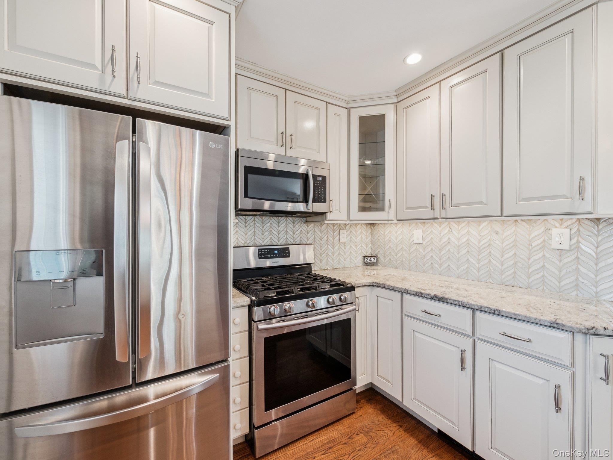 247 Woods Road North Babylon, NY 11703 - Photo 9 of 43 a kitchen with stainless steel appliances white cabinets and a stove top oven