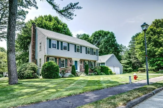 a front view of a house with a yard and trees