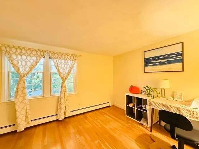 a view of an empty room with a window and wooden floor