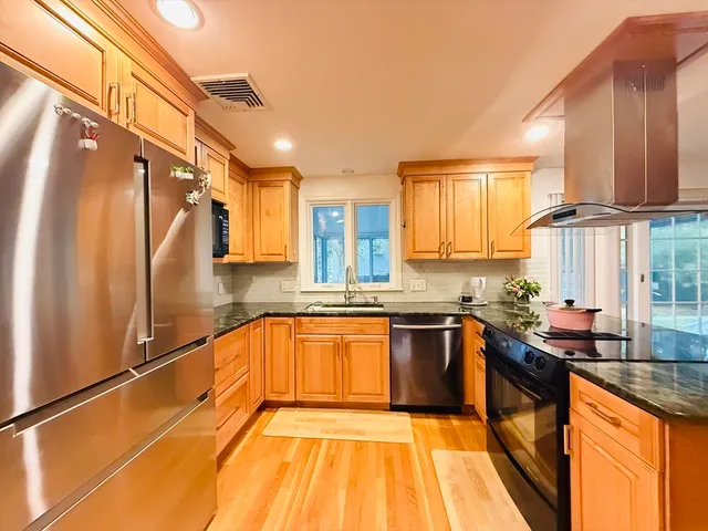 a kitchen with stainless steel appliances granite countertop sink stove refrigerator and cabinets